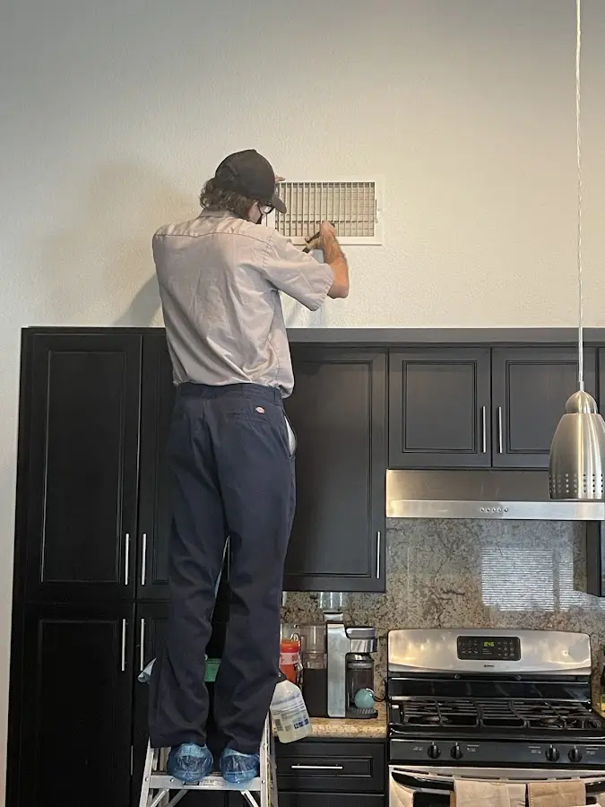 Technician inspecting an air vent during HVAC service in Bristol